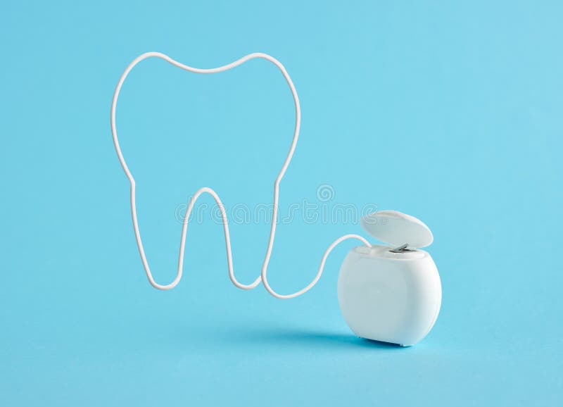 Tooth symbol made of dental floss on blue background. Dental health, hygiene and tooth care concept. Tooth symbol made of dental floss on blue background. Dental health, hygiene and tooth care concept