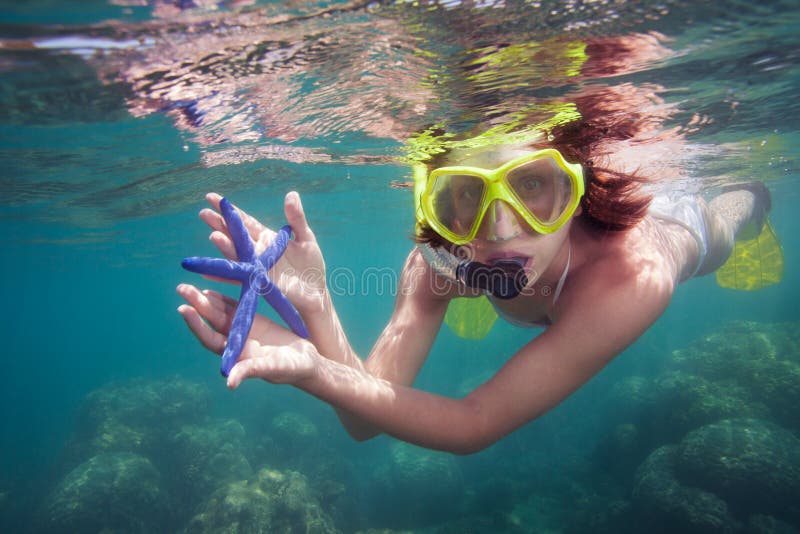 Snorkeler holding blue starfish and looking into camera. Snorkeler holding blue starfish and looking into camera