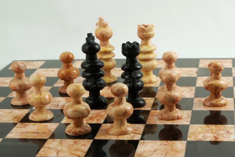 White pieces surrounding the black king and queen on a chessboard, ambush concept. White pieces surrounding the black king and queen on a chessboard, ambush concept.