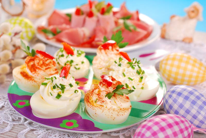 Egg halves stuffed with cheese and mayonnaise decorated with red pepper and chives for easter. Egg halves stuffed with cheese and mayonnaise decorated with red pepper and chives for easter