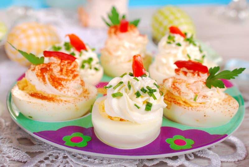 Egg halves stuffed with cheese and mayonnaise decorated with red pepper and chives for easter. Egg halves stuffed with cheese and mayonnaise decorated with red pepper and chives for easter