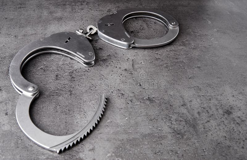 Police handcuff on rough grey background with copy space. Police handcuff on rough grey background with copy space.