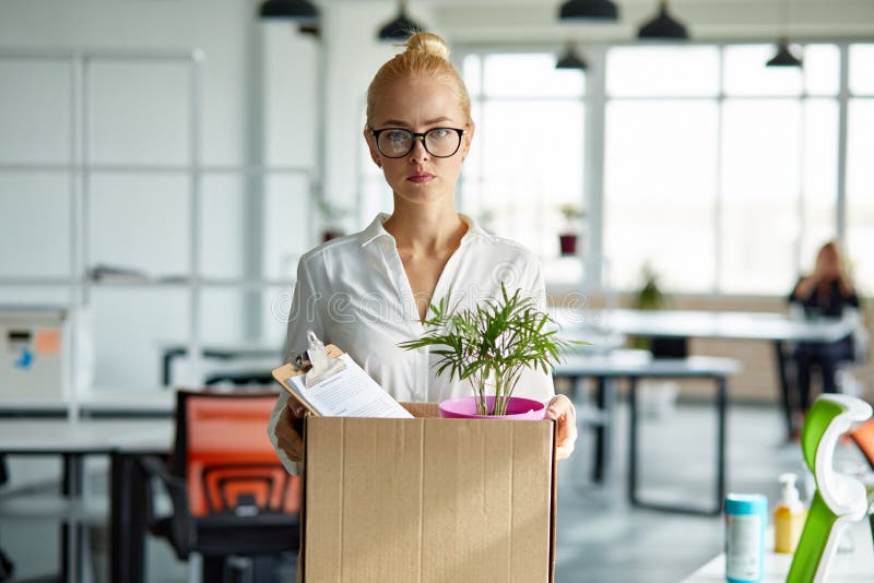 Sad dismissed female worker is taking her office supplies from office, packing in box. jobless female. Sad dismissed female worker is taking her office supplies from office, packing in box. jobless female