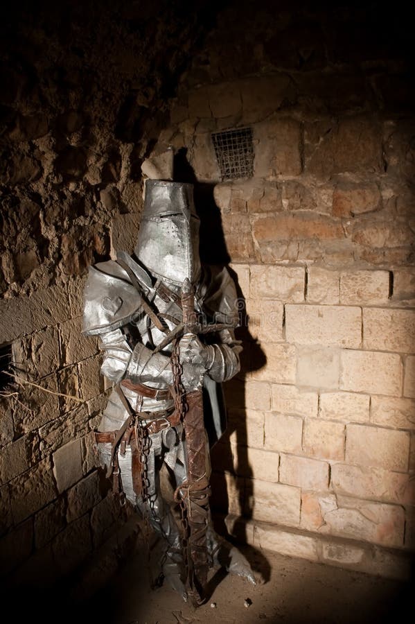 Imprisoned medieval knight lit by a shaft of light. Imprisoned medieval knight lit by a shaft of light