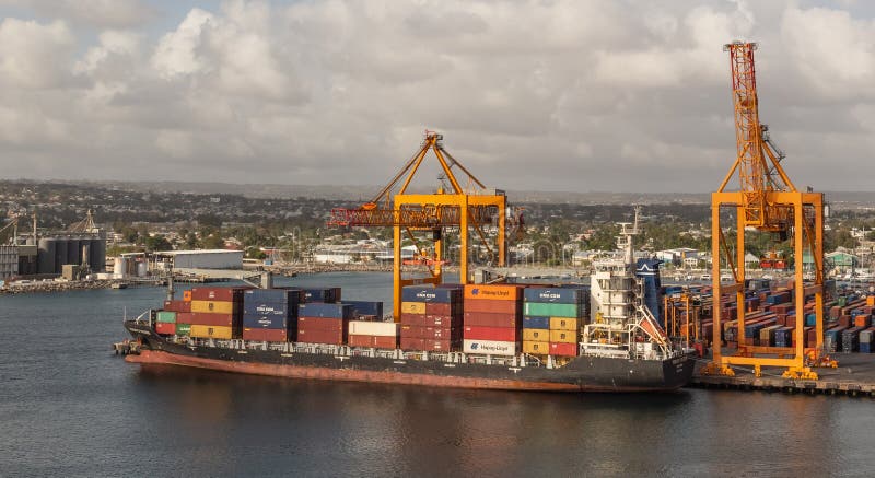 Bridgetown port, Barbados, West Indies - May 2, 2020: Bridgetown port with loading cranes and cargo ship being loaded with containers. Bridgetown port, Barbados, West Indies - May 2, 2020: Bridgetown port with loading cranes and cargo ship being loaded with containers