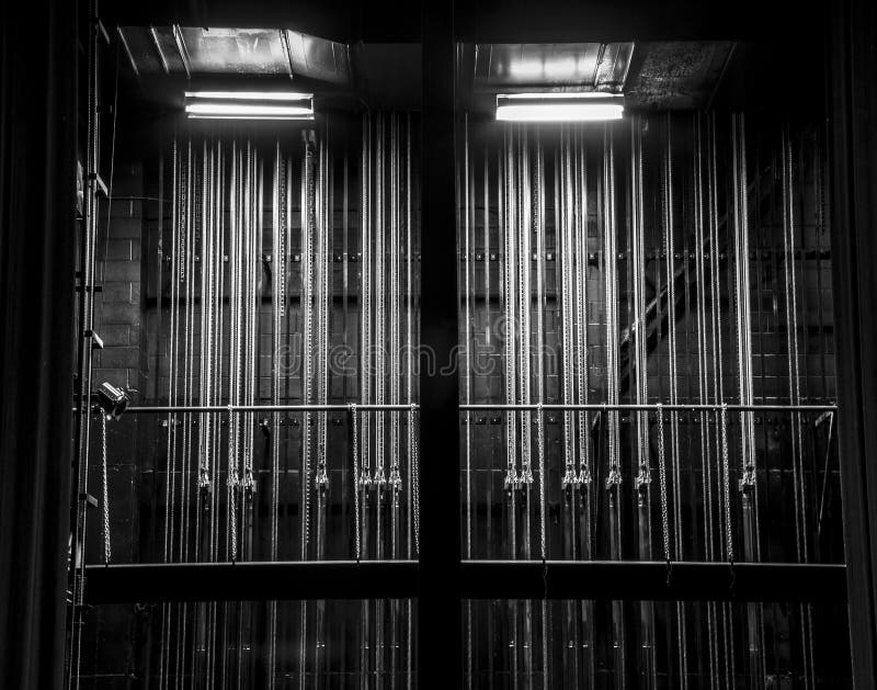 Cable and chain rigging backstage in a theater. Vertical lines. Black and white. Cable and chain rigging backstage in a theater. Vertical lines. Black and white.