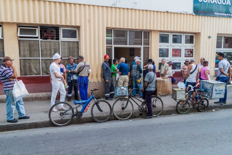 CIENFUEGOS, CUBA - FEBRUARY 10, 2016: Local people wait in a queue for bread in Cienfuegos, Cuba. CIENFUEGOS, CUBA - FEBRUARY 10, 2016: Local people wait in a queue for bread in Cienfuegos, Cuba.