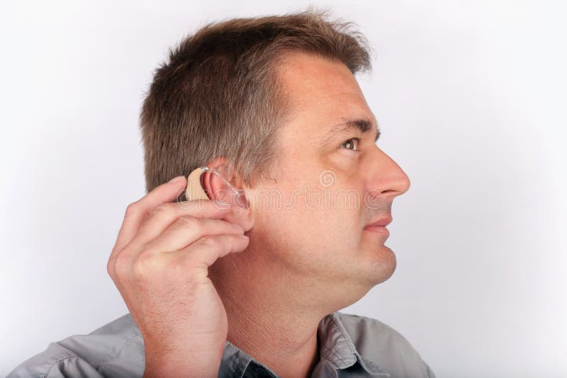 Senior man inserting his hearing aid. Senior man inserting his hearing aid