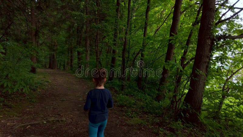 走在一条小径的女孩特写镜头，单独在黑暗，鬼的森林里
