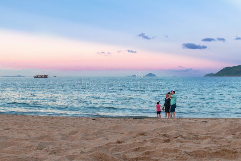 越南芽庄 — 2019年4月21日:海边有孩子的家庭和粉红的夕阳 免版税图库摄影 越南芽庄 — 2019年4月21日:海边有孩子的家庭和粉红的夕阳 免版税图库摄影
