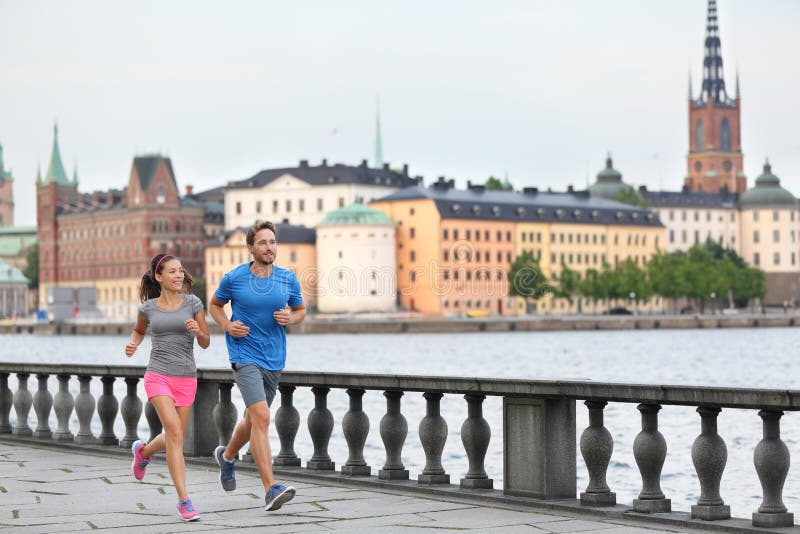 Fit fitness exercise people, healthy runners running in Stockholm city cityscape skyline. Riddarholmskyrkan church in the background, Sweden, Europe. Healthy multiracial young adults, asian woman, caucasian man. Fit fitness exercise people, healthy runners running in Stockholm city cityscape skyline. Riddarholmskyrkan church in the background, Sweden, Europe. Healthy multiracial young adults, asian woman, caucasian man.