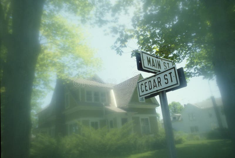 Street sign at corner of Main and Cedar with Victorian house in background, Michigan. Street sign at corner of Main and Cedar with Victorian house in background, Michigan