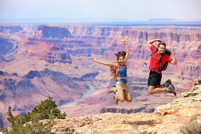 Happy people jumping in Grand Canyon. Young multiethnic couple on hiking travel. Grand Canyon, south rim, Arizona, USA. Happy people jumping in Grand Canyon. Young multiethnic couple on hiking travel. Grand Canyon, south rim, Arizona, USA.