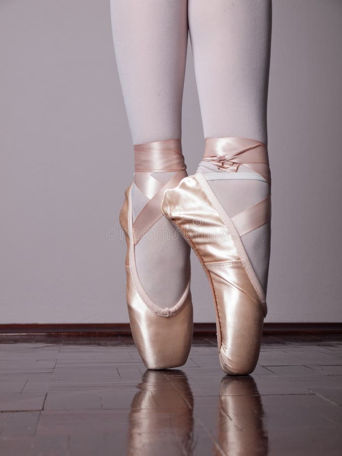 Low angle shot of a dancer in ballet shoes dancing in Pointe on wooden floor. Low angle shot of a dancer in ballet shoes dancing in Pointe on wooden floor