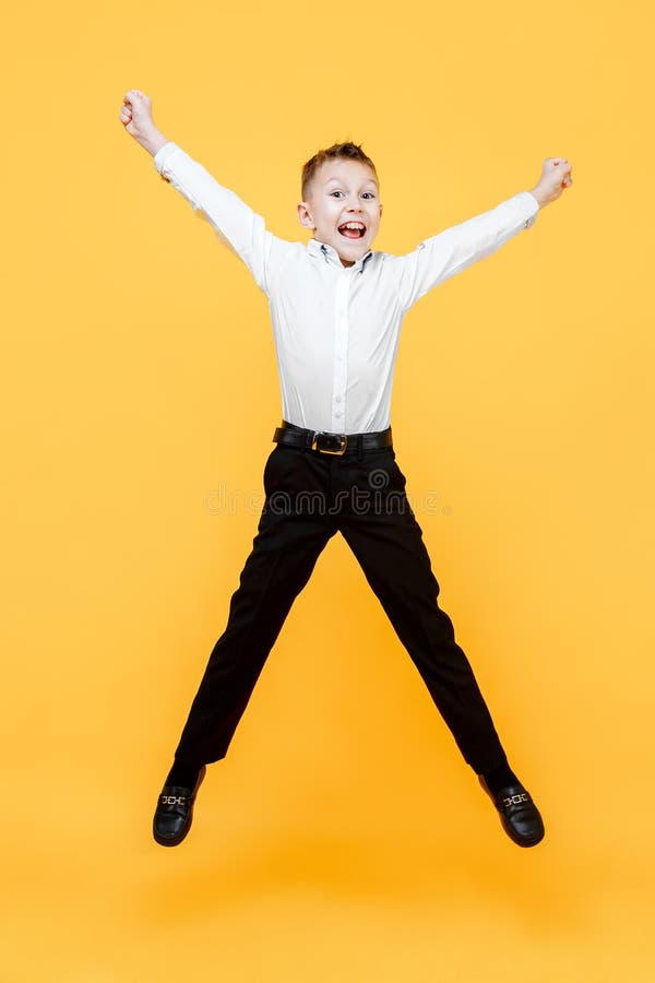 跳跃为喜悦的愉快的男小学生 幸福、活动和儿童概念