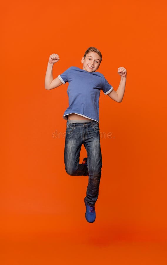 跳跃为在桔子的喜悦的愉快的男小学生