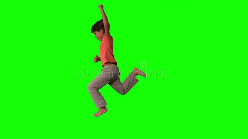 跳跃在绿色屏幕上的男孩侧视图