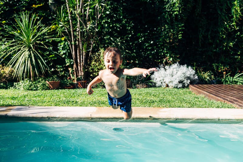 Little boy jumping in a pool. Child get fun in the swimming pool of his home. Outdoors activities in quarantine. Little boy jumping in a pool. Child get fun in the swimming pool of his home. Outdoors activities in quarantine
