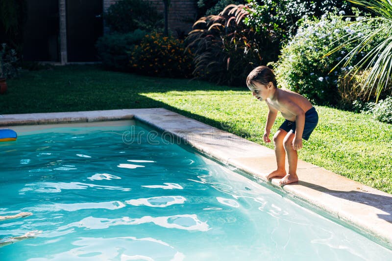 Little boy jumping in a pool. Child get fun in the swimming pool of his home. Outdoors activities in quarantine. Little boy jumping in a pool. Child get fun in the swimming pool of his home. Outdoors activities in quarantine