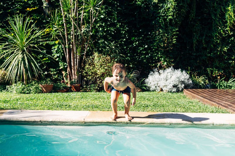 Little boy jumping in a pool. Child get fun in the swimming pool of his home. Outdoors activities in quarantine. Summer sesason. Little boy jumping in a pool. Child get fun in the swimming pool of his home. Outdoors activities in quarantine. Summer sesason.