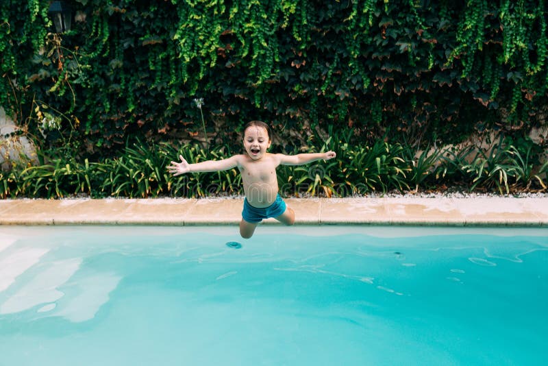 Little boy jumping into a pool. Child get fun in the swimming pool of his home. Outdoors activities in quarantine. In home. Little boy jumping into a pool. Child get fun in the swimming pool of his home. Outdoors activities in quarantine. In home