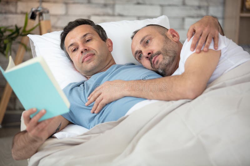 躺在床上看书的男人 库存照片