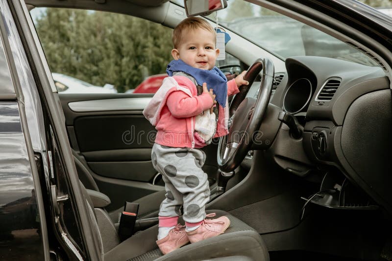 车里的小孩 站在驾驶座上,握住方向盘 车门开着 婴儿驾驶 那孩子看起来 免版税库存照片 车里的小孩 站在驾驶座上,握住方向盘 车门开着 婴儿驾驶 那孩子看起来 免版税库存照片