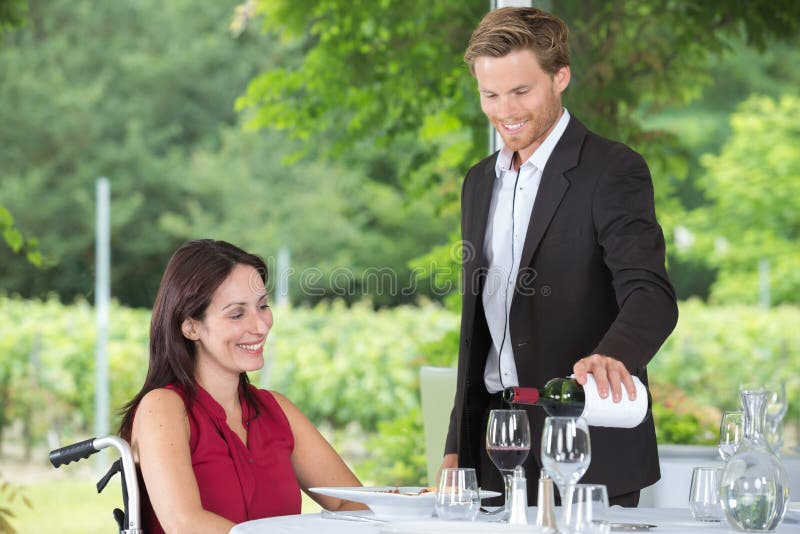 坐在轮椅上的女子在咖啡馆吃午饭 图库摄影