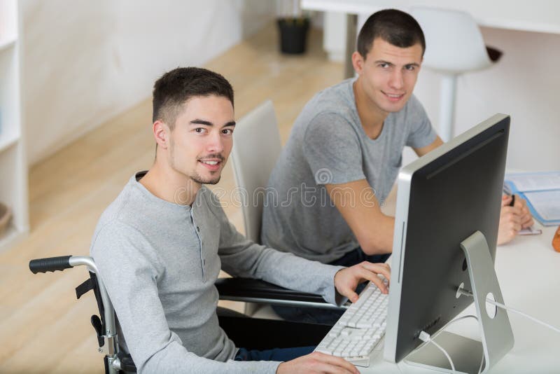 学生坐在轮椅上在教室里打字 免版税库存照片