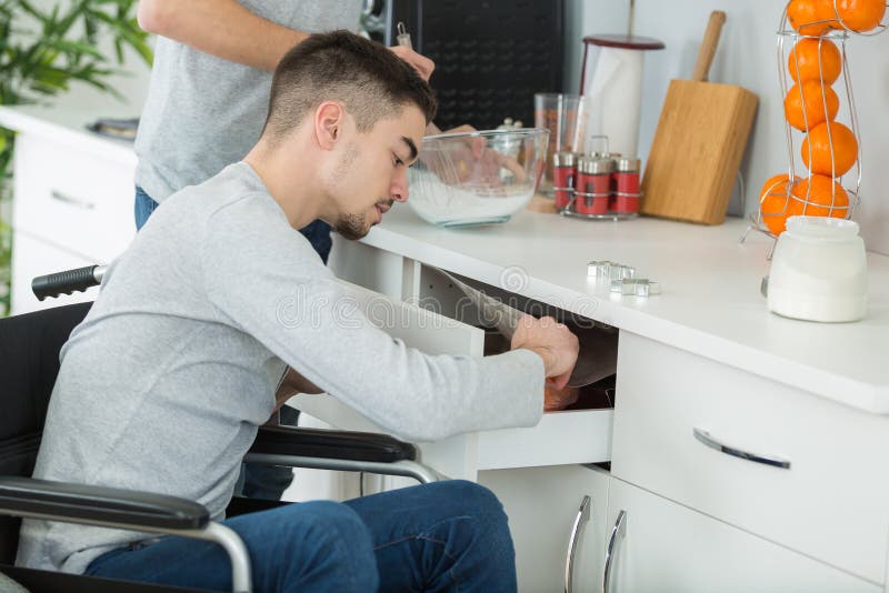 年轻男子在厨房的轮椅上 免版税库存照片