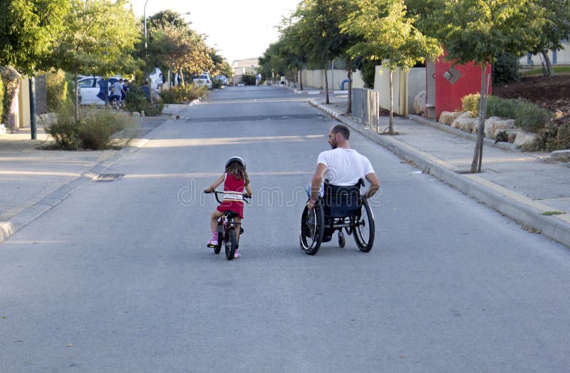 Man in a Wheelchair, Teaching his Daughter to Ride the Bicycle. Man in a Wheelchair, Teaching his Daughter to Ride the Bicycle