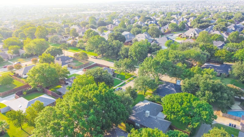 Urban sprawl near Dallas, Texas, USA with row of single family houses and large fenced backyard. Aerial view residential neighborhood subdivision surrounded by mature trees in early summer morning. Urban sprawl near Dallas, Texas, USA with row of single family houses and large fenced backyard. Aerial view residential neighborhood subdivision surrounded by mature trees in early summer morning