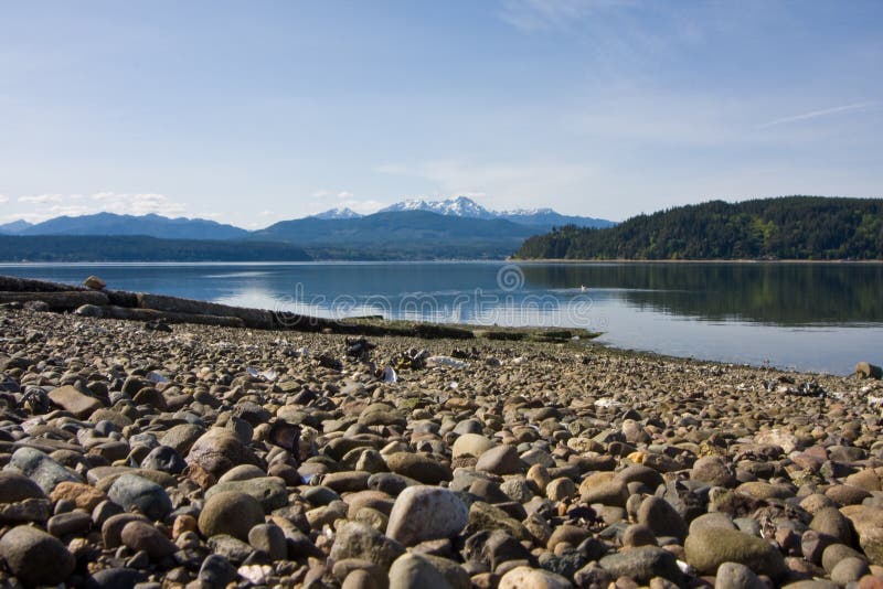 Hood Canal Washington with Olympic Mountains in background with rocky beach reflection shot. Hood Canal Washington with Olympic Mountains in background with rocky beach reflection shot