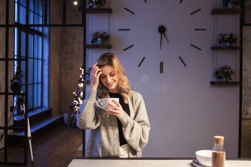 迷人的女孩在厨房里在早晨 谈话在电话和有有杯子的早餐A年轻女人在她的手上 免版税库存照片 迷人的女孩在厨房里在早晨 谈话在电话和有有杯子的早餐A年轻女人在她的手上 免版税库存照片