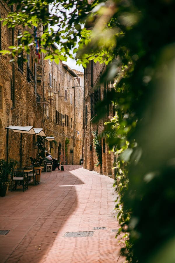 迷人的欧洲小巷，铺着鹅卵石小路，有古朴的咖啡馆和茂盛的绿植，构成一幅如画的城市景象。意大利托斯卡纳 库存照片