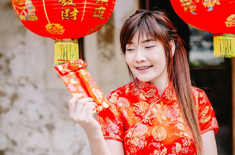 迷住美丽的亚洲女服cheongsam礼服的画象从她的家庭得到红色信封 俏丽的女孩显示红色信封 P 免版税库存图片 迷住美丽的亚洲女服cheongsam礼服的画象从她的家庭得到红色信封 俏丽的女孩显示红色信封 P 免版税库存图片