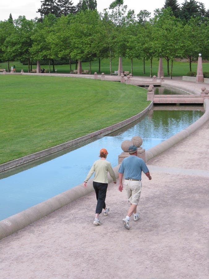 A middle-aged couple walks in a city park to keep fit. A middle-aged couple walks in a city park to keep fit.