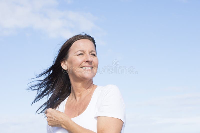 Portrait attractive mature woman joyful and happy retired, keeping healthy and fit, isolated on blue sky background and with copy space. Portrait attractive mature woman joyful and happy retired, keeping healthy and fit, isolated on blue sky background and with copy space.