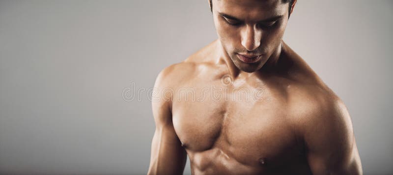 Portrait of fit masculine shirtless man looking down. Wide panoramic crop with copy space. Workout and fitness theme. Portrait of fit masculine shirtless man looking down. Wide panoramic crop with copy space. Workout and fitness theme.