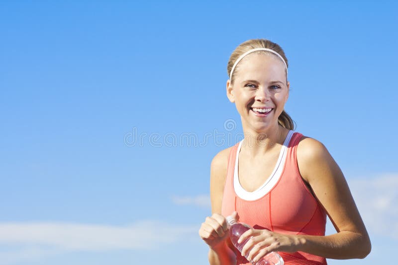 A happy, healthy and fit woman drinking a bottled water after a workout. A happy, healthy and fit woman drinking a bottled water after a workout