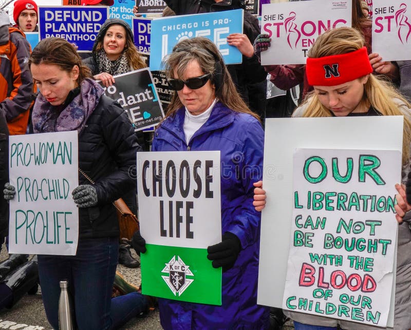 Washington, DC - January 27, 2017: Women kneeling and holding signs advocate against abortion during the annual March for Life. Washington, DC - January 27, 2017: Women kneeling and holding signs advocate against abortion during the annual March for Life.