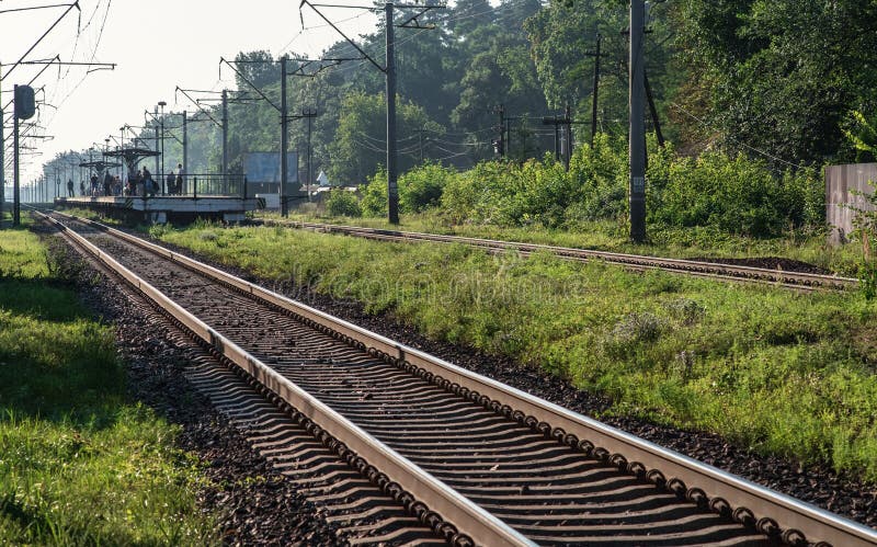 Suburban train waiting platform. Electrified railway tracks stretch into the distance. Selective focus. Suburban train waiting platform. Electrified railway tracks stretch into the distance. Selective focus