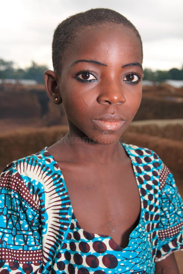 A young African girl in Sonyon, a flat-roofed village east of Bole town in North-Western Ghana (Western Africa). She has a ritual scare on her cheek that marks her tribal identity. Scarification of faces has been long practiced in Akan societies of Ghana, thought nowadays the tradition becomes less common. The community in Sonyon is known for its bizarre architecture - flat-roofed houses attached to each other, forming platforms on roofs for walking and spending time. Access to the houses is through their roofs and with the use of wooden ladders. In the past, these architectural features served as defensive traits against animals and enemies. A young African girl in Sonyon, a flat-roofed village east of Bole town in North-Western Ghana (Western Africa). She has a ritual scare on her cheek that marks her tribal identity. Scarification of faces has been long practiced in Akan societies of Ghana, thought nowadays the tradition becomes less common. The community in Sonyon is known for its bizarre architecture - flat-roofed houses attached to each other, forming platforms on roofs for walking and spending time. Access to the houses is through their roofs and with the use of wooden ladders. In the past, these architectural features served as defensive traits against animals and enemies.