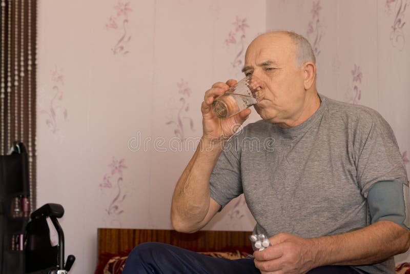 Elderly man taking his medication drinking the tablets down with a glass of water. Elderly man taking his medication drinking the tablets down with a glass of water