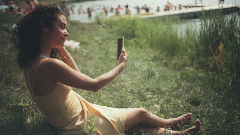 采取在电话的年轻美丽的妇女selfie，当坐草时
