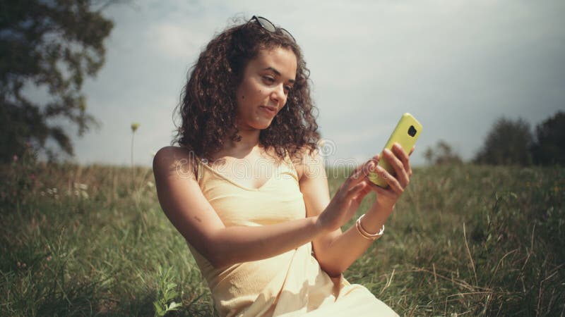 采取在电话的年轻美丽的妇女selfie，当坐草时