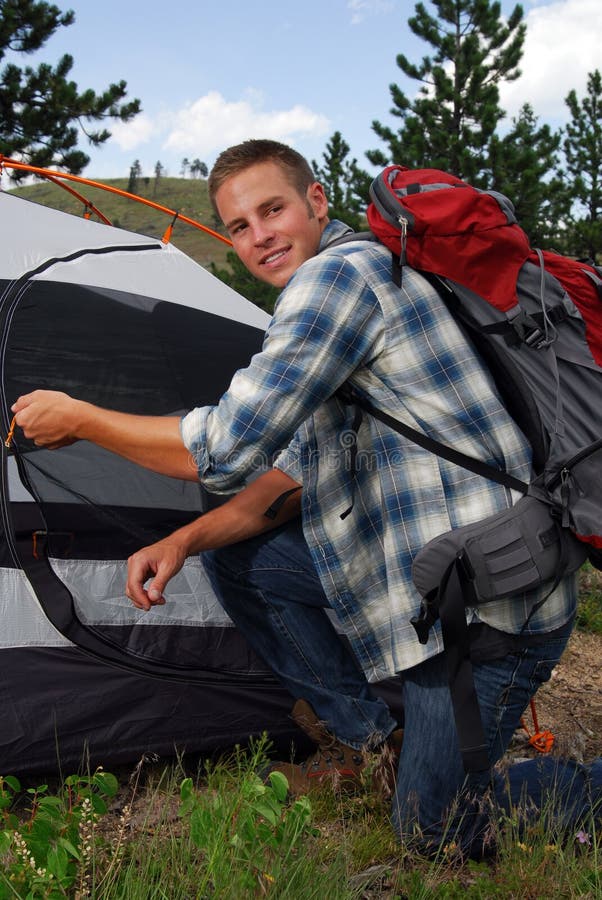 A backpacker zipping up his camping tent. A backpacker zipping up his camping tent