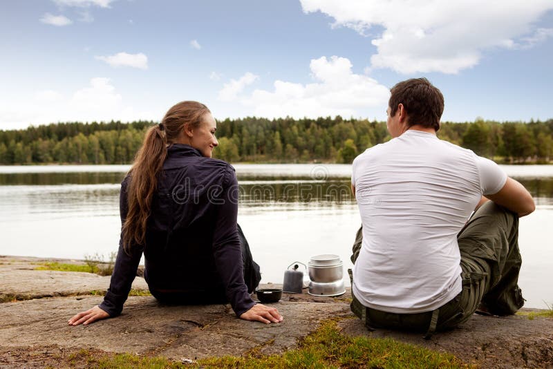 A man and woman happy camping in the forest by a lake. A man and woman happy camping in the forest by a lake