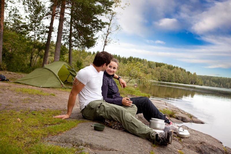 A man and woman happy camping in the forest by a lake. A man and woman happy camping in the forest by a lake