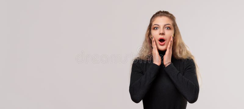 金发女孩张着大嘴,震惊地站着,带着难以置信的双手,近在眼前,感觉有些呆滞和惊讶. 我不敢相信这是真的. 张着嘴巴、近脸手的惊吓女孩的肖像. 真实的人类反应情绪和感受. 工作室背景灰色. 广告位置